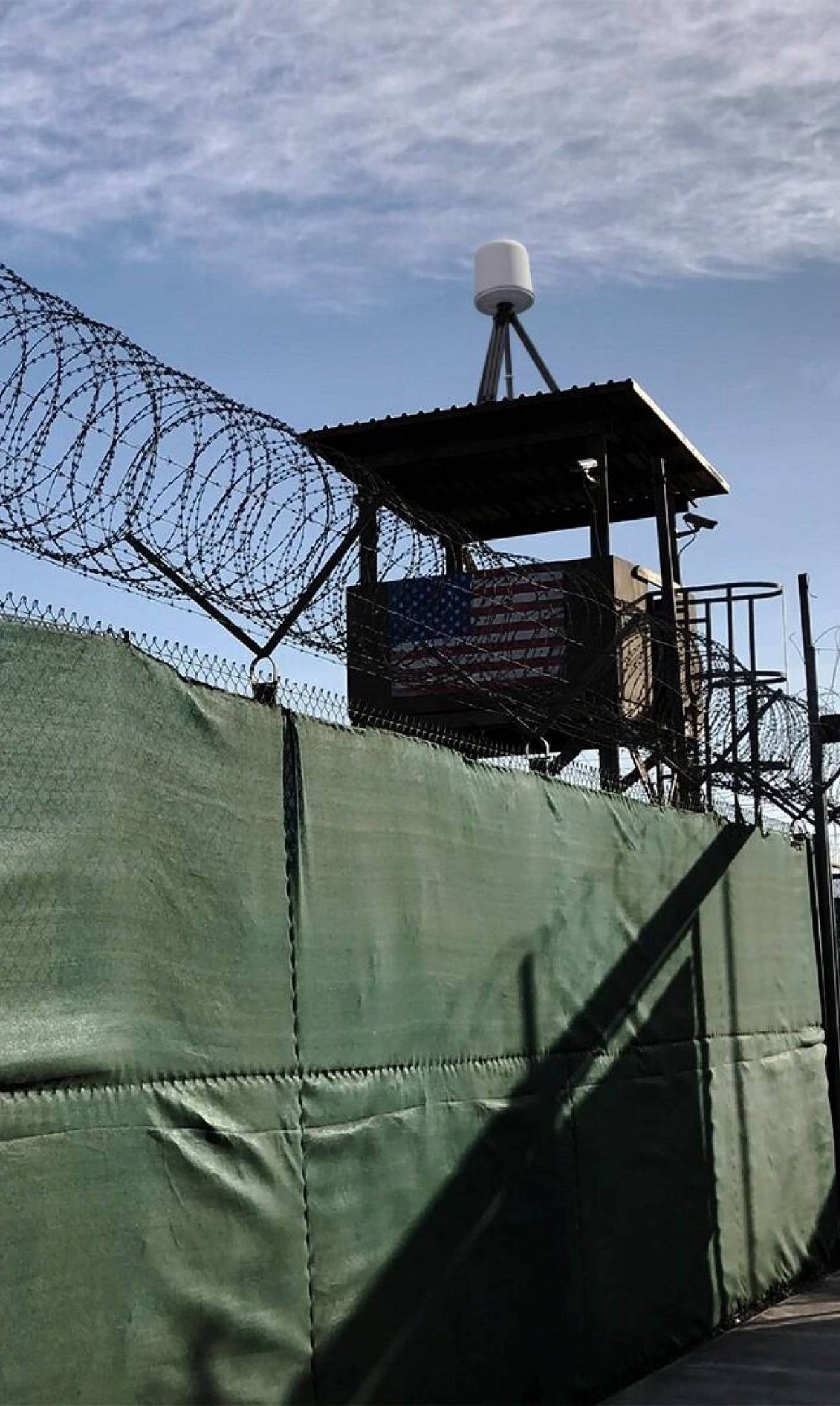 Military base perimeter fence enclosing a watchtower with an IRIS drone detection radar on the roof