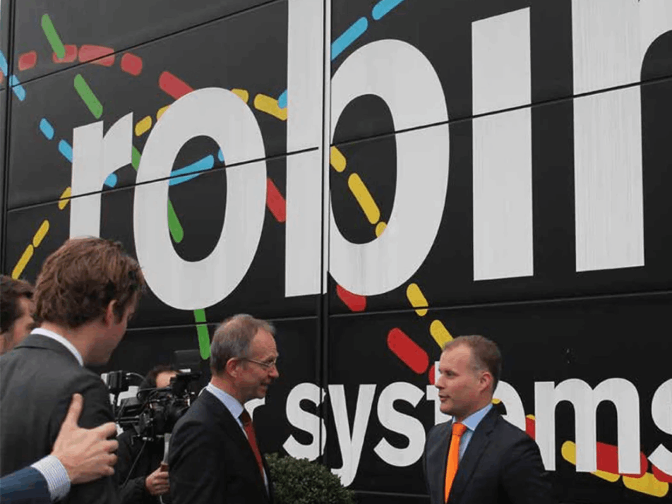 Siete talking to the Dutch government in front of a large wall decorated in Robin's colours